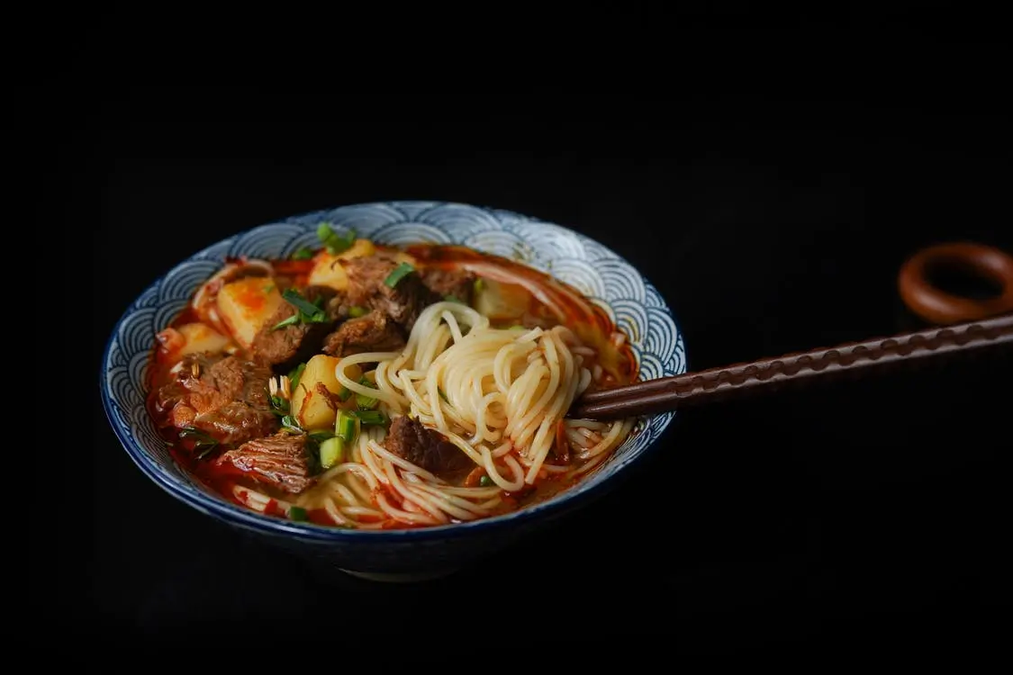 Bowl of spicy beef noodle soup with chopsticks, garnished with green onions Bowl of spicy beef noodle soup with chopsticks, garnished with green onions